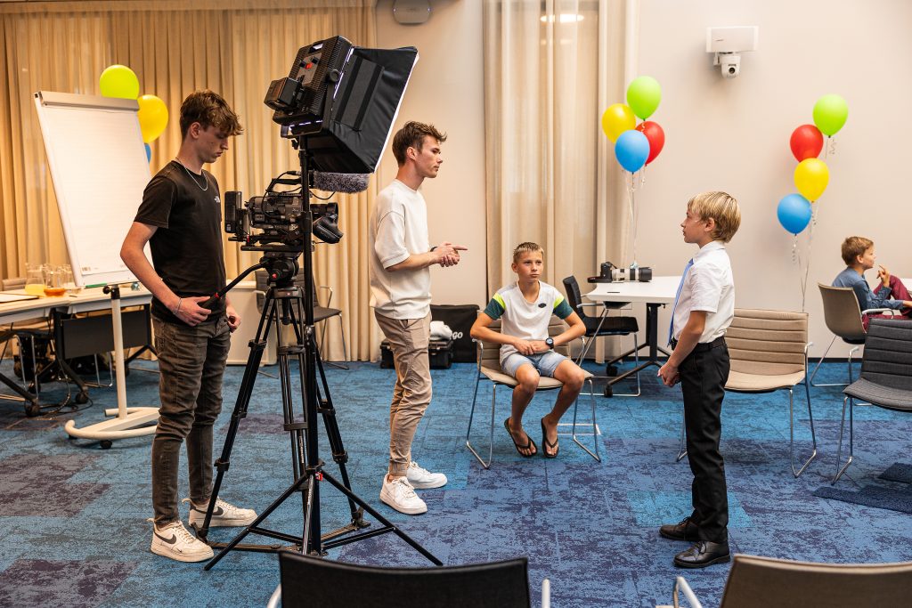 Mannen en kinderen staan bij camera in raadzaal