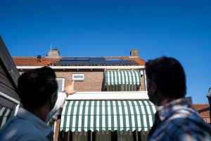 Twee mannen kijken en wijzen naar de zonnepanelen op een woning