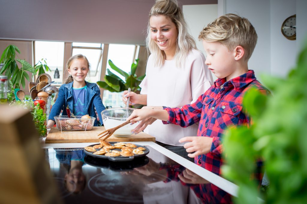 Moeder met 2 kinderen staan poffertjes te maken in de keuken