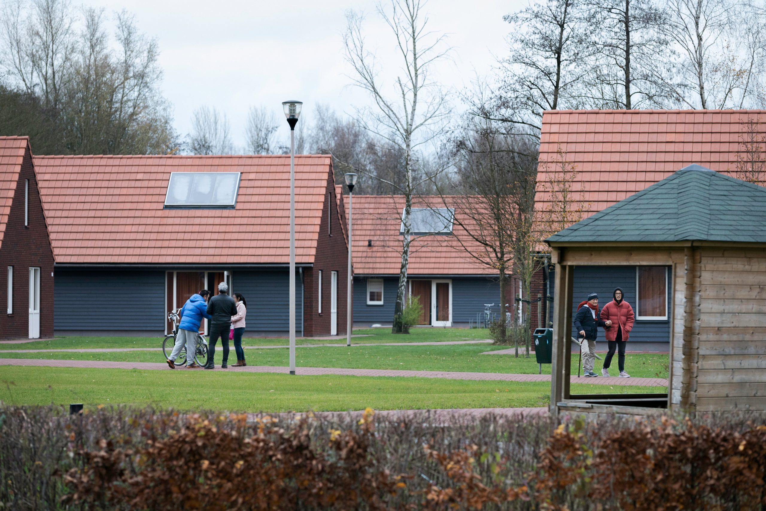 een azc waar in de tuin vluchtelingen rondlopen