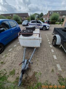 verwaarloosde wit met rode aanhanger zonder kenteken aan de Nic. Beetslaan, vlakbij nummer 168 op de parkeerplaats. Op de aanhanger liggen twee wielen.