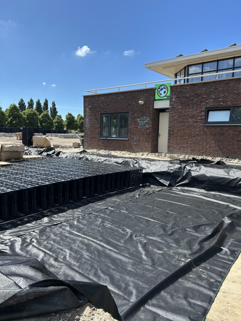 Een grondzeil met daarop honderden kratten staan klaar tijdens het aanleggen van de waterberging bij Voetbalvereniging ASW.