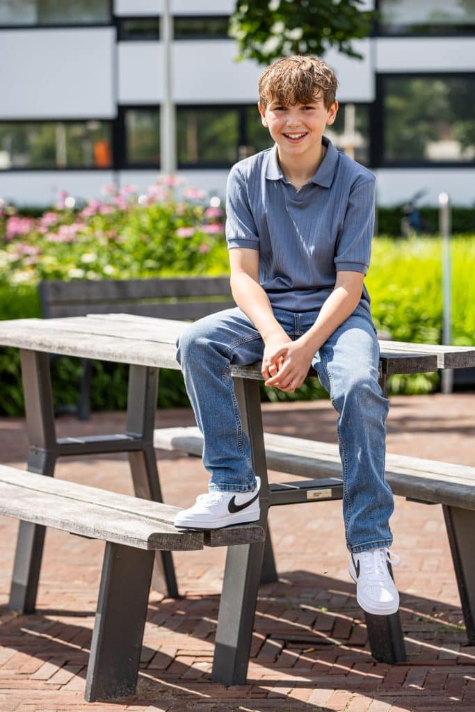 Jongen zit op picknicktafel.